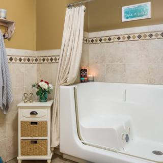 A cozy bathroom featuring a walk-in tub, adorned with elegant tiles and soft lighting from a lit candle.