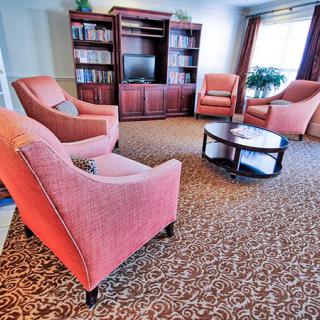 A cozy living room with armchairs, a bookshelf, and a television.