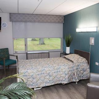 A modern hospital room featuring a bed, window with natural light, and tasteful decor.