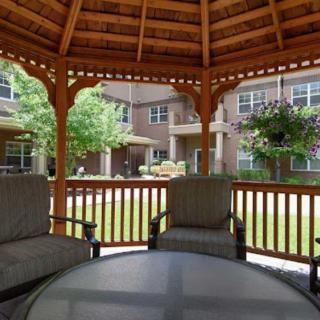 A cozy gazebo with comfortable chairs in a garden setting at an apartment complex.