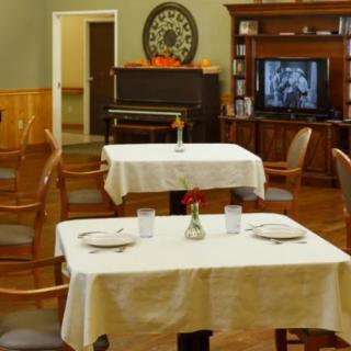 A cozy dining room with neatly arranged tables and a television in the corner.