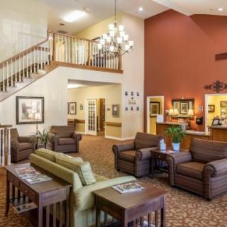 A spacious and comfortable lobby with seating areas, a staircase, and a chandelier.
