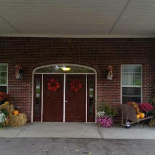 A welcoming entrance adorned with autumn decorations and colorful flowers.