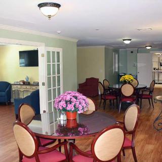 A cozy dining area with round tables and chairs, adorned with flowers, adjacent to a living space.