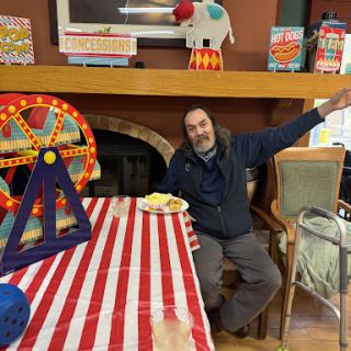A man enjoying refreshments at a festive indoor carnival-themed gathering.