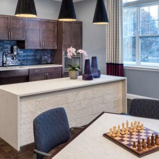 A modern kitchen interior with a chessboard on the table and elegant lighting.