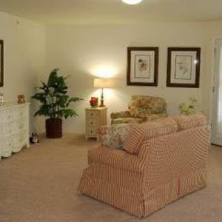 A cozy living room featuring a sofa, armchair, lamp, indoor plant, and wall art.