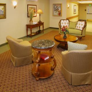 A cozy lobby seating area with comfortable chairs, wooden tables, and decorative art on the walls.