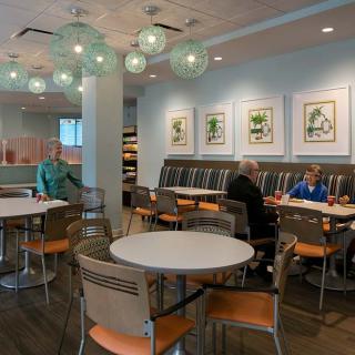 A modern cafe interior with round tables, chairs, and artwork on the walls.