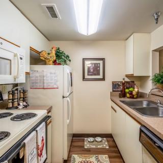 A cozy, compact kitchen with white appliances and traditional decor.