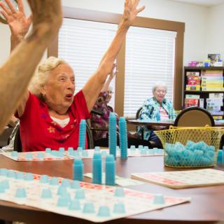 Elderly woman celebrates during a lively bingo game at a community center.