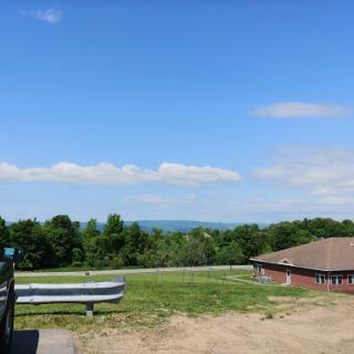 A serene view of rolling hills under a clear blue sky, with a building in the foreground.