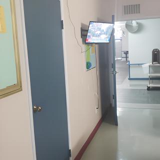 A hallway with a door and a wall-mounted monitor.