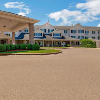 A large hotel building with a covered entrance and driveway under a partly cloudy sky.