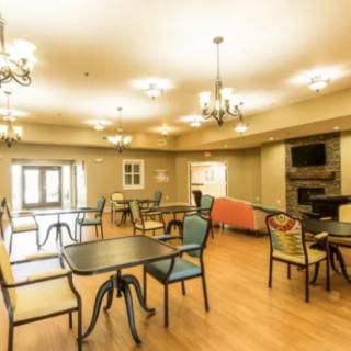 A spacious dining room with multiple tables and chairs, illuminated by elegant chandeliers.