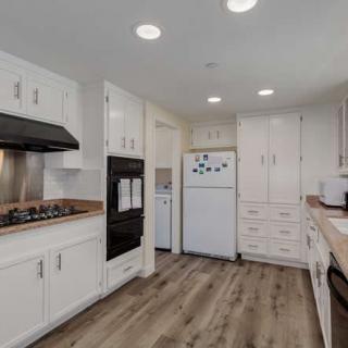 A modern kitchen featuring white cabinets and wood flooring.