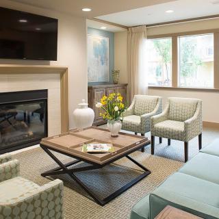 A modern living room with a cozy seating area, featuring a fireplace and ample natural light.