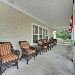 A covered porch with a row of wicker chairs featuring striped cushions.