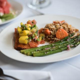 A gourmet dinner plate featuring asparagus, a vegetable medley, and seasoned grains.