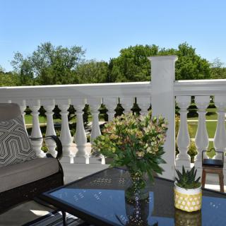 A cozy balcony with comfortable seating and potted plants offers a serene outdoor escape on a sunny day.
