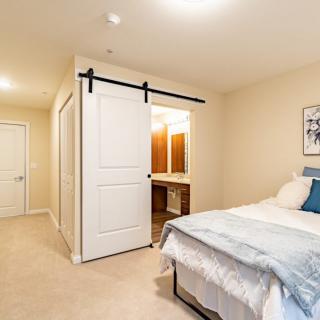 A cozy bedroom featuring a bed with blue accents, sliding closet doors, and soft lighting.