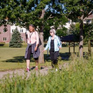 Two people enjoying a walk in the park on a sunny day.