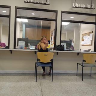 A woman sitting in a waiting area, likely at a customer service office.