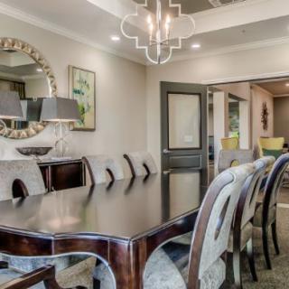 An elegantly designed dining room featuring a polished wooden table, upholstered chairs, and a stylish chandelier.