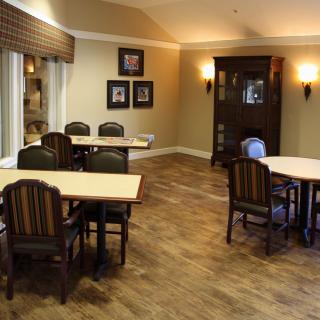 A cozy dining area with wooden tables and chairs, set in a warmly decorated interior.