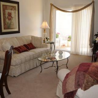 A cozy and elegantly decorated living room with a sofa, glass coffee table, lamp, and wall art.