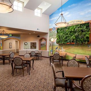 A dining area with tables and chairs, featuring a mural on the wall and skylights overhead.