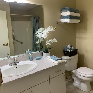 A neatly organized bathroom with a sink, mirror, and decorative flowers.