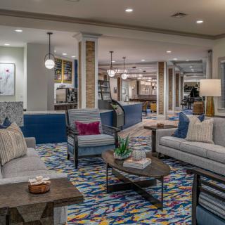 A modern lobby area featuring comfortable sofas, a colorful carpet, and stylish lighting.