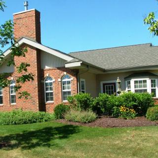 A brick house with well-maintained landscaping and a green lawn.