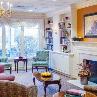 A cozy living room with a fireplace, elegant furniture, and a bookshelf.