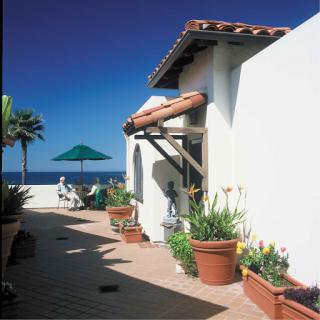 A serene coastal view highlighting a charming building with lush greenery and the ocean in the background.