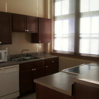 A well-lit kitchen with wooden cabinets and a countertop.