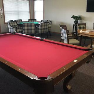 A cozy game room featuring a pool table with red felt and comfortable seating areas.