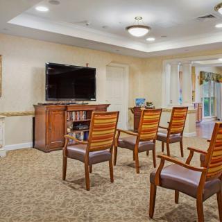 A cozy seating area with chairs facing a television in a well-lit room.