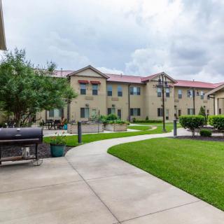 A residential building with a well-maintained lawn and pathway under a cloudy sky.