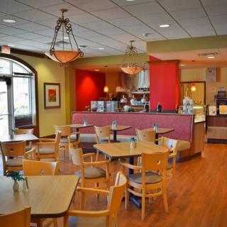 A cozy cafe interior with wooden tables and chairs, warm lighting, and inviting decor.