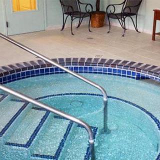 An indoor jacuzzi with steps leading in, surrounded by a tiled floor and seating area.