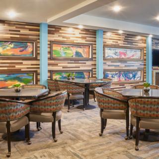 A well-decorated restaurant interior featuring colorful wall art, neatly arranged tables and chairs, and ambient lighting.