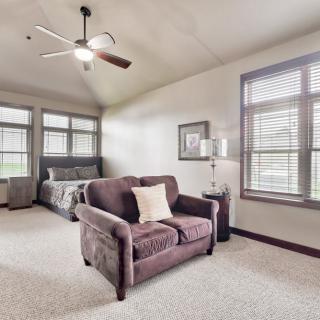 A spacious bedroom with a cozy sofa, bed, and large windows.