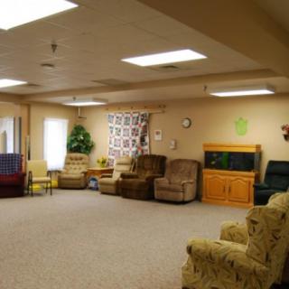 A spacious living room with various chairs and a sofa, decorated with wall art and a carpeted floor.