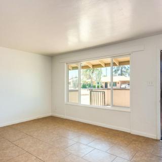 A bright and empty room with a large window and tile flooring.