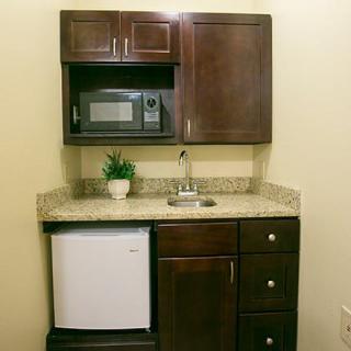 A compact kitchenette with a microwave, mini fridge, and granite countertop.