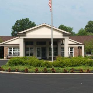 A building entrance with an American flag and surrounding greenery.