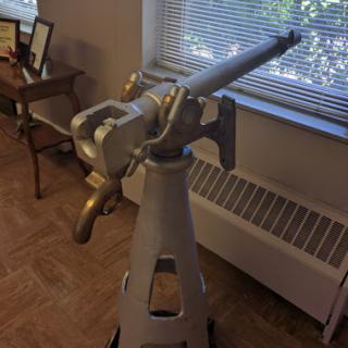 A vintage telescope positioned by a window, surrounded by wooden furniture.