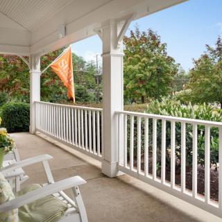 A cozy porch with rocking chairs overlooking a garden and trees.